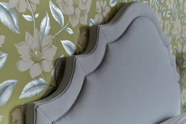 Ornate Curved Shape with Border and Buttons Bardsey Headboard upholstered in Pure Cotton Ice Blue Fabric with Self Piping and No Buttons in a Jardin Des Plantes Green and White Floral Wallpapered Room